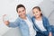 Young adult woman and her little daughter sitting together on couch, making selfie