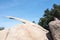 Young adult woman hiker attempts to get on top of Potato Chip Rock in Ramona California in San Diego