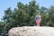 Young adult woman hiker stands on top of a giant boulder rock in San Diego California