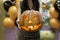 Young adult woman hold in hand spooky custom weird handmade orange pumpkin head with carved faces and glowing candle or