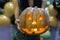 Young adult woman hold in hand spooky custom weird handmade orange pumpkin head with carved faces and glowing candle or