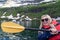 Young adult woman kayaks on Cameron Lake in Waterton National Park, enjoying the glacier scenery
