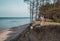 Young adult woman in pink hat sitting alone on the bluffs, looking of sea, freedom concept, peaceful atmosphere