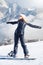 Young adult woman snowboarder standing on a snowboard one foot in the clasp of the other in the snow e