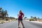 Young adult woman stands in the middle of a lone desert highway in Joshua Tree National Park