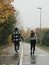 Young adults enjoying a rainy day outdoors by taking a stroll along a road through woods