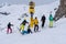 Young adults in winter, stand in line on a slope wearing skis, snowboard on a cloudy day