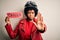 Young African American afro motorcyclist woman with curly hair holding danger paper message with open hand doing stop sign with