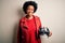 Young African American afro motorcyclist woman with curly hair holding motorcycle helmet with a happy and cool smile on face