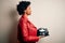 Young African American afro motorcyclist woman with curly hair holding motorcycle helmet looking to side, relax profile pose with