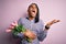 Young african american afro romantic man with dreadlocks holding bouquet of pink tulips crazy and mad shouting and yelling with