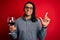 Young african american afro sommelier man with dreadlocks drinking glass of wine surprised with an idea or question pointing