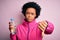 Young African American afro sportswoman with curly hair drinking bottle of water with angry face, negative sign showing dislike