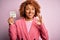 Young African American afro woman with curly hair holding papaer with tax day message doing ok sign with fingers, excellent symbol