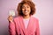 Young African American afro woman with curly hair holding papaer with tax day message with a happy face standing and smiling with