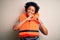 Young African American afro woman with curly hair wearing orange protection lifejacket smiling in love doing heart symbol shape