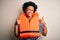 Young African American afro woman with curly hair wearing orange protection lifejacket success sign doing positive gesture with