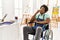 Young african american artist man sitting on wheelchair at art studio looking stressed and nervous with hands on mouth biting