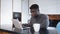 Young african american black man working on laptop in his appartment and drinking tea or coffee