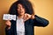 Young african american business woman with afro hair holding help paper for work stress with angry face, negative sign showing