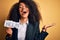 Young african american business woman with afro hair holding help paper for work stress very happy and excited, winner expression