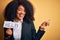 Young african american business woman with afro hair holding help paper for work stress very happy pointing with hand and finger