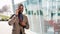 Young African American businessman stands next to the modern office talks on his smartphone. He talks to his business