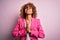 Young african american businesswoman wearing glasses standing over pink background begging and praying with hands together with
