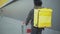 Young African American courier with yellow food delivery bag pushing shopping cart in urban city. Man with dreadlocks