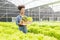 Young African American farmer worker inspects organic hydroponic plants with care and smiles happily: