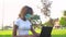 Young african american female student in protective mask working on laptop in park during covid 19 pandemic