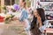 Young african american florist talking on smartphone while standing with colleague and working with flowers