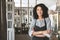 Young African American girl in apron standing with arms folded in restaurant. Nice girl with dark curly hair standing in