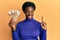 Young african american girl holding 5000 hungarian forint banknotes smiling with an idea or question pointing finger with happy