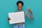 Young african american girl holding blank empty banner smiling happy and positive, thumb up doing excellent and approval sign