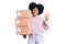 Young african american girl holding delivery package doing ok sign with fingers, smiling friendly gesturing excellent symbol