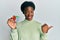 Young african american girl playing colorful puzzle cube intelligence game pointing thumb up to the side smiling happy with open