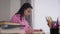 Young African American girl sitting at the table and writing down teacher`s lecture. Male Caucasian teacher in suit