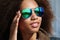 Young african american girl in sunglasses, posing outdoors, Dressed casual, with short voluminous hair.