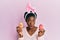 Young african american girl wearing cute easter bunny ears holding painted eggs afraid and shocked with surprise and amazed