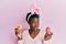 Young african american girl wearing cute easter bunny ears holding painted eggs smiling looking to the side and staring away