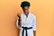 Young african american girl wearing karate kimono and black belt angry and mad raising fist frustrated and furious while shouting