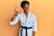 Young african american girl wearing karate kimono and black belt showing and pointing up with fingers number three while smiling