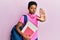 Young african american girl wearing school bag and holding books with open hand doing stop sign with serious and confident