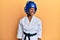 Young african american girl wearing taekwondo kimono and protection helmet looking to side, relax profile pose with natural face