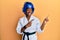 Young african american girl wearing taekwondo kimono and protection helmet smiling and looking at the camera pointing with two