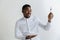 Young african american guy holding empty dish and fork with disgusting facial expression isolated on grey background.