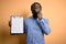 Young african american inspector man wearing glasses holding clipboard checklist serious face thinking about question, very