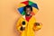 Young african american journalist man wearing yellow raincoat and umbrella cap pointing finger to one self smiling happy and proud
