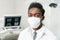 Young African American male doctor dentist in a medical mask. Medicine, health, stomatology concept. Looking into the